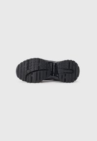 Sole di sneaker in gomma nera con un motivo di battistrada testurizzato, con scanalature e rilievi per una migliore aderenza. Design della parte centrale liscia e curvata.