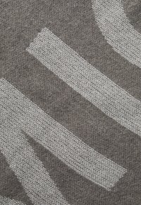 Tappeto grigio con larghe strisce bianche irregolari in un motivo tessuto testurizzato. Il materiale sembra morbido e resistente.