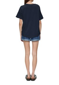 Marineblauw katoenen t-shirt met korte mouwen, ontspannen pasvorm en afgeronde zoom. Gecombineerd met denimshorts en instap sandalen.