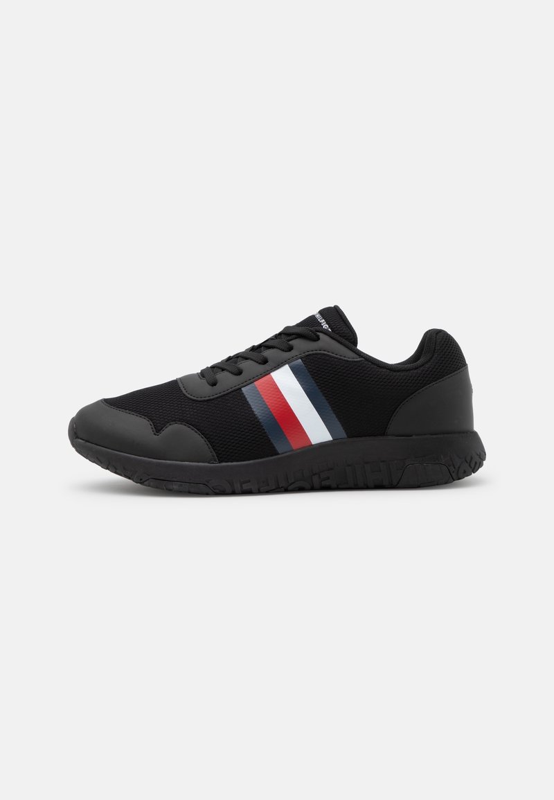 Chaussure de sport noire avec un matériau en mesh, une semelle en caoutchouc et un design rayé coloré en rouge, blanc et bleu sur le côté.