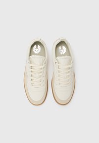 Białe skórzane sneakersy o zaokrąglonym kształcie, tekstylny język, beżowa gumowa podeszwa i srebrne akcenty logo na wkładkach.
