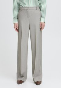 Pantalones de pierna ancha gris claro con un tejido texturizado, que cuentan con bolsillos delanteros y una cintura entallada. Combinados con una camisa verde a rayas.