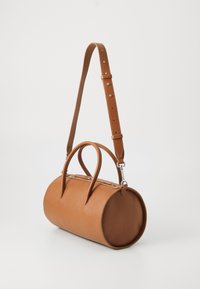 Brown leather handbag with a rounded shape, dual top handles, and a detachable, adjustable strap. Features a textured surface and zip closure.