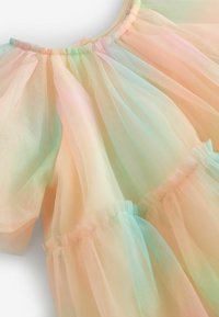 Robe en tulle pastel avec un design doux et superposé, dotée de manches bouffantes. Les couleurs passent d'un rose clair à un vert menthe. Accents volants sur les bords.