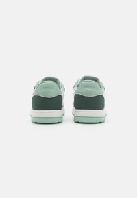 Green and white sneakers with a smooth leather upper and suede accents. Features a padded collar and a textured rubber sole.