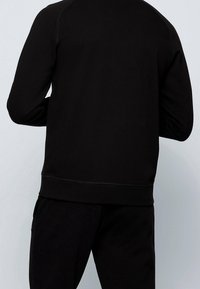 Svart sweatshirt i bomullsblandning, med rund halsringning, långa ärmar och kontrasterande sömmar längs sömmarna. Elastisk nederkant.