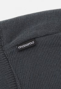 Tissu tricoté gris foncé, présentant un tissage texturé et une étiquette noire proéminente avec le nom de la marque "maximo" en lettres blanches.
