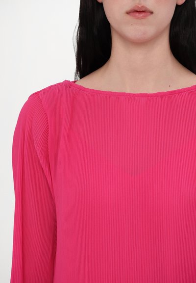 Lange mouwen, felroze blouse met een ribbeltextuur en een brede, ronde halslijn, met subtiele plooien bij de schouders.