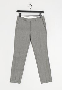 Šedé kalhoty s texturovaným povrchem, s plochým předním dílem, bočními kapsami a slim fit střihem. Stylizováno s černým ramínkem pro prezentaci.