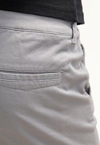 Grijze katoenen broek met een soepele textuur, voorzien van een zijzak, riemlussen en subtiele stikdetails.