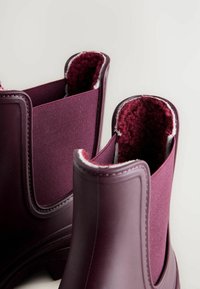 Bottines à la cheville en bourgogne imperméables avec matériaux en caoutchouc, côtés en textile, doublure douce et bords lisses avec des textures contrastantes.