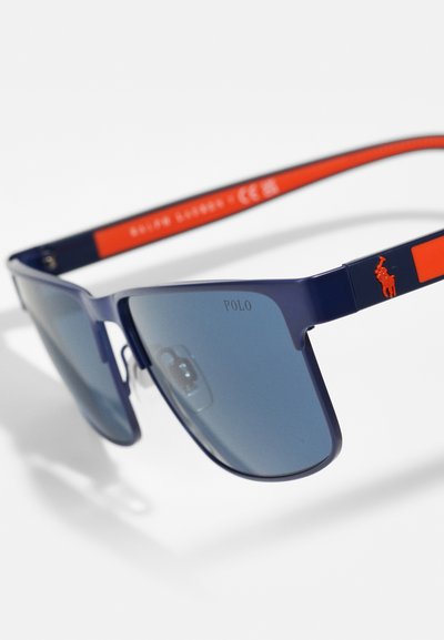 Granatowe okulary przeciwsłoneczne z gradientowymi niebieskimi soczewkami, prostokątnym kształtem, akcentem w postaci czerwonego logo Polo na zauszniku oraz lekką plastikową oprawką.