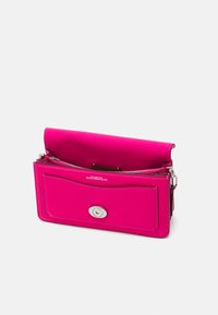 Pink leather handbag with a smooth texture, rectangular shape, front zip pocket, and a circular silver snap closure. Opened to show interior.