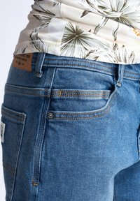 Blauwe spijkerbroek met een klassieke pasvorm, subtiele stikseldetails, vijf zakken en een leren label op de tailleband.