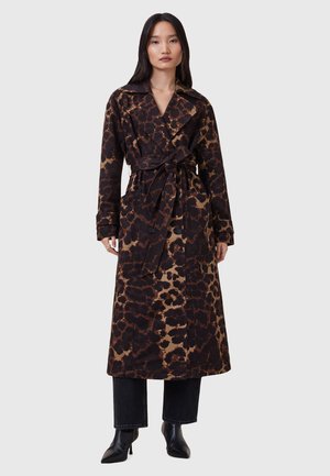 Duga, smeđa trench jakna s leopard uzorkom, s remenom u struku, velikim ovratnikom i dugmadima na džepovima, u kombinaciji s crnim hlačama i čizmama s visokom petom.