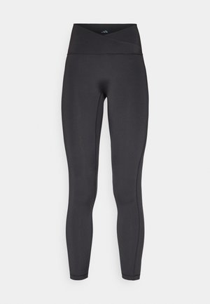 Leggings neri a vita alta con fascia incrociata, realizzati in tessuto elasticizzato, caratterizzati da una texture liscia e dettagli cuciti.