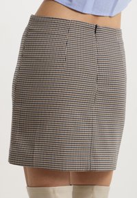 Mini gonna a motivo houndstooth in beige e blu navy, con un design attillato e cerniera nascosta sul retro. Texture liscia con finitura sartoriale.