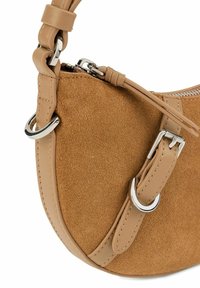 Borsa in suede beige con forma arrotondata, dettagli in pelle, accessori in metallo argentato e una tracolla decorativa con dettaglio della fibbia.