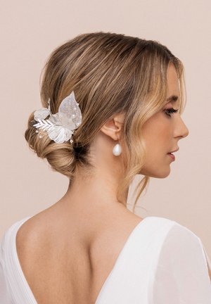 Accessorio per capelli argenteo con intricati design a foglia, accenti di glitter e piccoli perle, abbinato a un'acconciatura a chignon liscia.