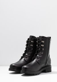 Stivaletti neri in pelle con punta rotonda, chiusura con lacci, dettagli in argento e suola in gomma texturizzata; dotati di cerniera laterale per una facile calzata.