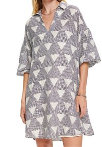 Femme portant une robe courte et ample avec un motif triangulaire géométrique noir et blanc et des manches ballon trois-quarts.