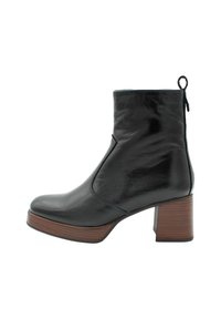 Bottine en cuir noir avec un talon carré, dotée d'un bout arrondi et d'une fermeture éclair sur le côté, ornée d'une semelle texturée marron.