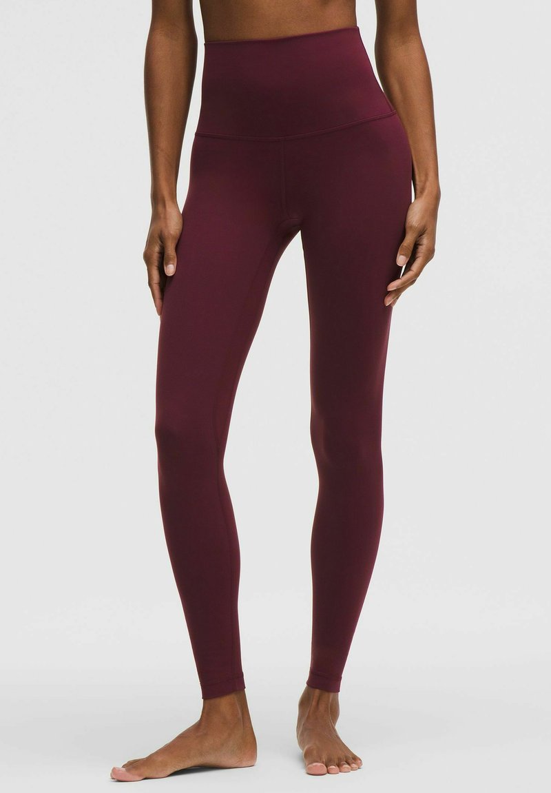 Donkerrode leggings met hoge taille gemaakt van een glad, rekbaar materiaal. Het aansluitende ontwerp loopt door tot de enkels, met een naadloze uitstraling en zonder zichtbare stiksels.