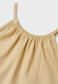 Top sans manches jaune clair avec des détails élastiques froncés le long de l'encolure et des fines bretelles, en tissu de coton doux.