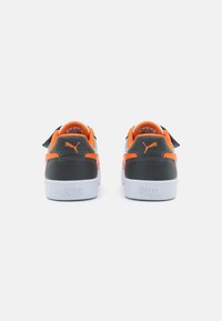 Baskets noires et orange avec un col rembourré, semelle intermédiaire blanche et couture contrastante. Logo Puma sur le talon et les côtés latéraux.