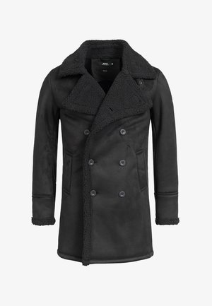 Schwarzer, doppelt geknöpfter Mantel mit breitem Lammfellkragen und -manschetten, zwei Fronttaschen und strukturiertem Fleece-Futter, das an Revers und Ärmelsäumen sichtbar ist.