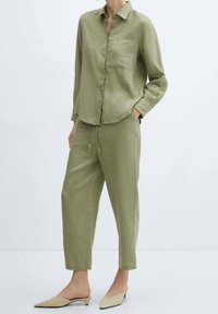Khaaki lniany koszula z guzikami z przodu i jedną kieszenią na piersi, połączona z dopasowanymi luźnymi spodniami z elastyczną talią.
