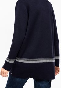 Marinblå tröja med långa ärmar, med ett silverfärgat horisontellt randmönster längs fållen. Tillverkad av mjukt, strukturerat tyg.