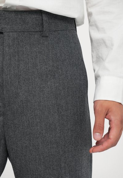 Šedé elegantné nohavice z textúrovaného materiálu, s úzkym strihom a pútkami na opasok, v rovnom prednom dizajne, skombinované s bielou košou.