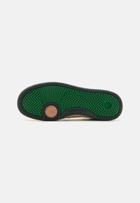Green rubber outsole with textured zigzag pattern, complemented by a brown circular accent. Lacosste branding is visible along the edge.