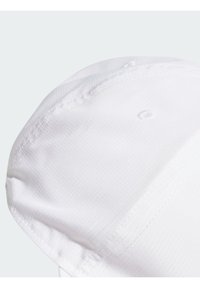 Gorra de béisbol blanca con una tela texturizada, corona redonda y costuras cosidas; presenta un pequeño orificio de ventilación circular en la parte superior.