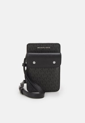 Bolso bandolera compacto negro Michael Kors con correa ajustable, bolsillo frontal con solapa asegurado por dos botones plateados y patrón de monograma MK.