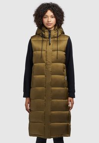 Long olive green puffer vest with a hood, featuring a quilted design, front zip, and adjustable drawstrings. Black sleeves visible underneath.