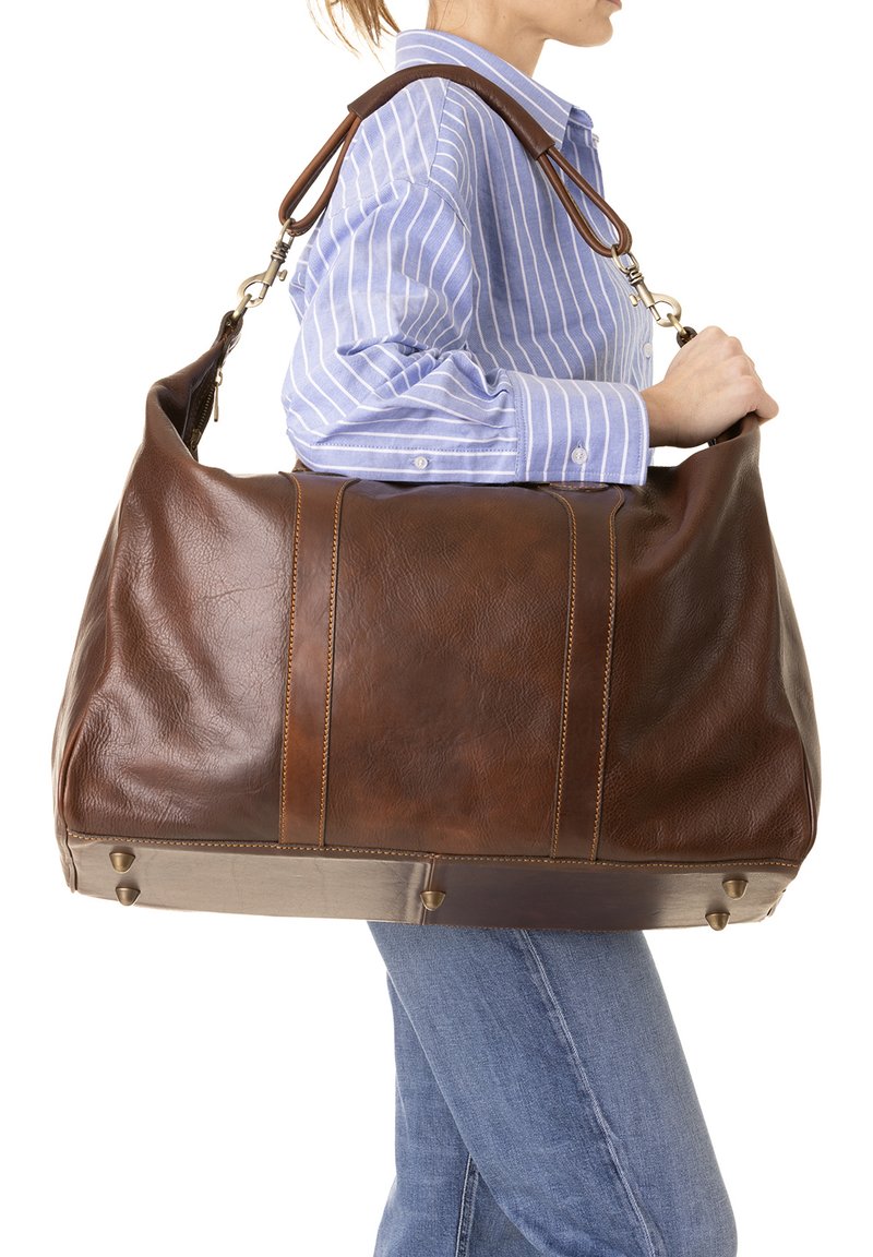 Bruine leren weekendtas met een gestructureerde afwerking, uitgerust met twee handgrepen aan de bovenkant, een ritssluiting en metalen pootjes voor stabiliteit. Versterkt met stiksels.