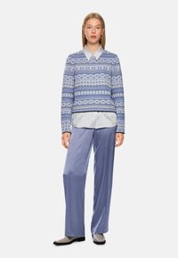 Light blue patterned sweater with a collar, paired with loose light lavender trousers and beige boots. Soft fabric and relaxed fit.