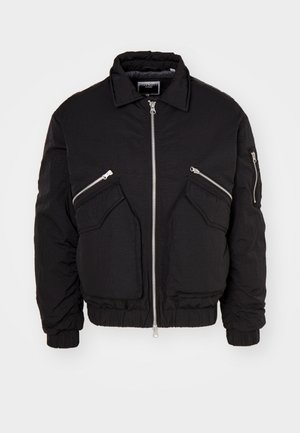 Jachetă bomber neagră cu fermoar frontal, două buzunare laterale înclinate și mâneci cu manșete ribolate. Fabricată dintr-un material texturat cu o croială lejeră.