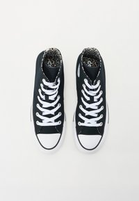 Sorte kanvas høye sneakers med hvite snørebånd, gummitåhettene og leopardmønstret fôr. Har en svart og hvit stripet såle.