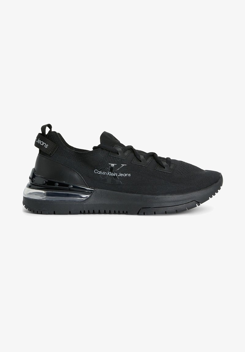 Black athletic shoes with a textured fabric upper, lace closure, and transparent midsole. Features branding on the side and heel tab.