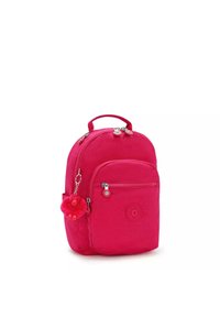 Zaino in tessuto rosa con forma arrotondata, tasca anteriore con zip e un portachiavi che raffigura una scimmietta di peluche. Presenta il logo sul lato.