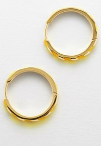 Orecchini a cerchio in oro con un design texturizzato, caratterizzati da accenti arancioni che creano un effetto a strati. Finitura liscia con una lucentezza brillante.