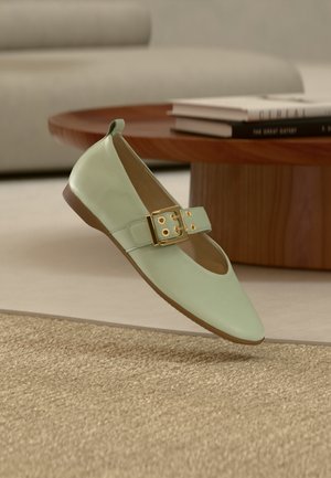 Tyrkysově zelená balerína s kulatou špičkou, širokým páskem a zlatou sponou. Hladká kožená textura a minimalistický design.