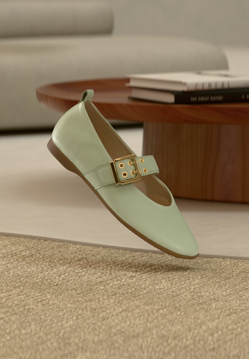 Πλατφόρμα παπούτσι σε μέντα πράσινο με στρογγυλεμένη μύτη, με φαρδιά λουρί και χρυσό αγκράφα. Λείο δέρμα και μινιμαλιστικός σχεδιασμός.