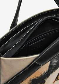 Borsa a spalla in ecopelle nera con esterno in tela stampata. Dotata di più scomparti e cuciture resistenti. L'interno è in tessuto nero.