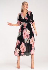 Czarna plisowana sukienka z kwiecistym wzorem w odcieniach różu i kremu, z dekoltem w serek, trzema cząstkami rękawów oraz paskiem w talii.