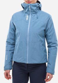 Veste imperméable bleu clair avec un col haut, fermeture éclair à l'avant et capuche ajustable. Présente un logo et un marquage GORE-TEX sur les manches.