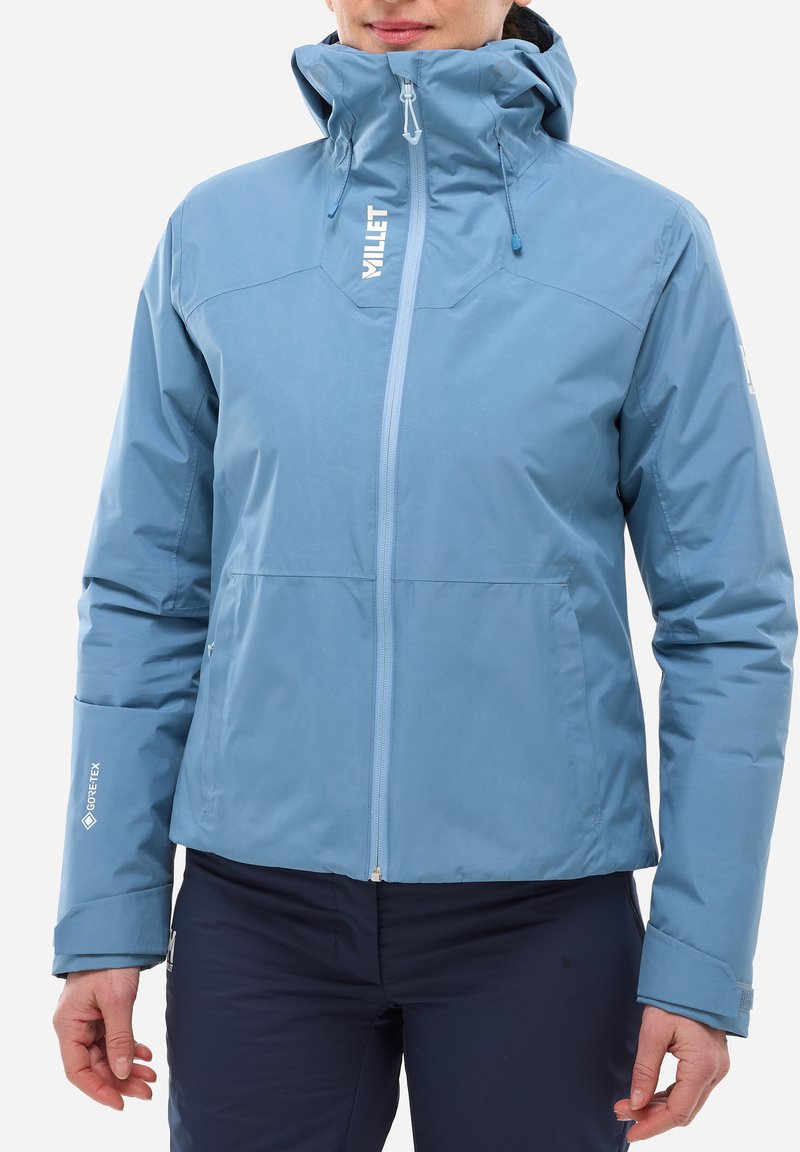 Veste imperméable bleu clair avec un col haut, fermeture éclair à l'avant et capuche ajustable. Présente un logo et un marquage GORE-TEX sur les manches.